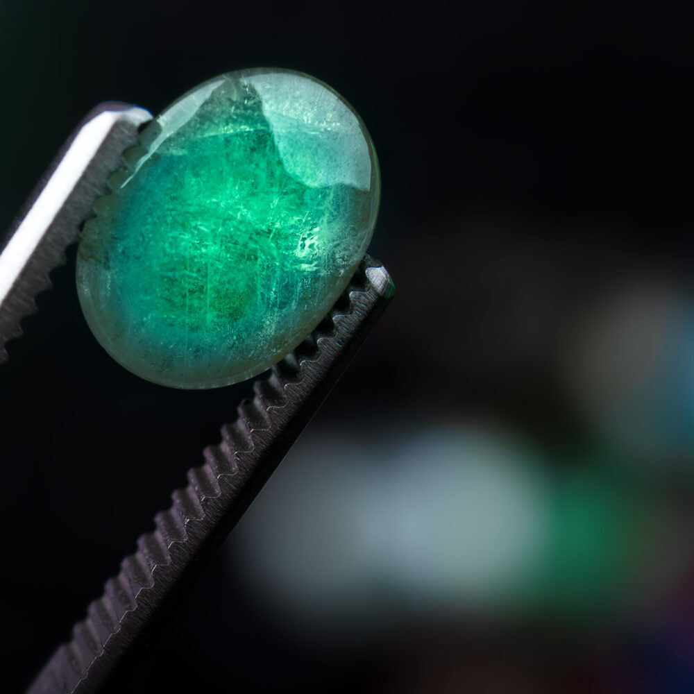 Emerald gemstone in the forcep. Emerald gemstone in the forcep with dark background.